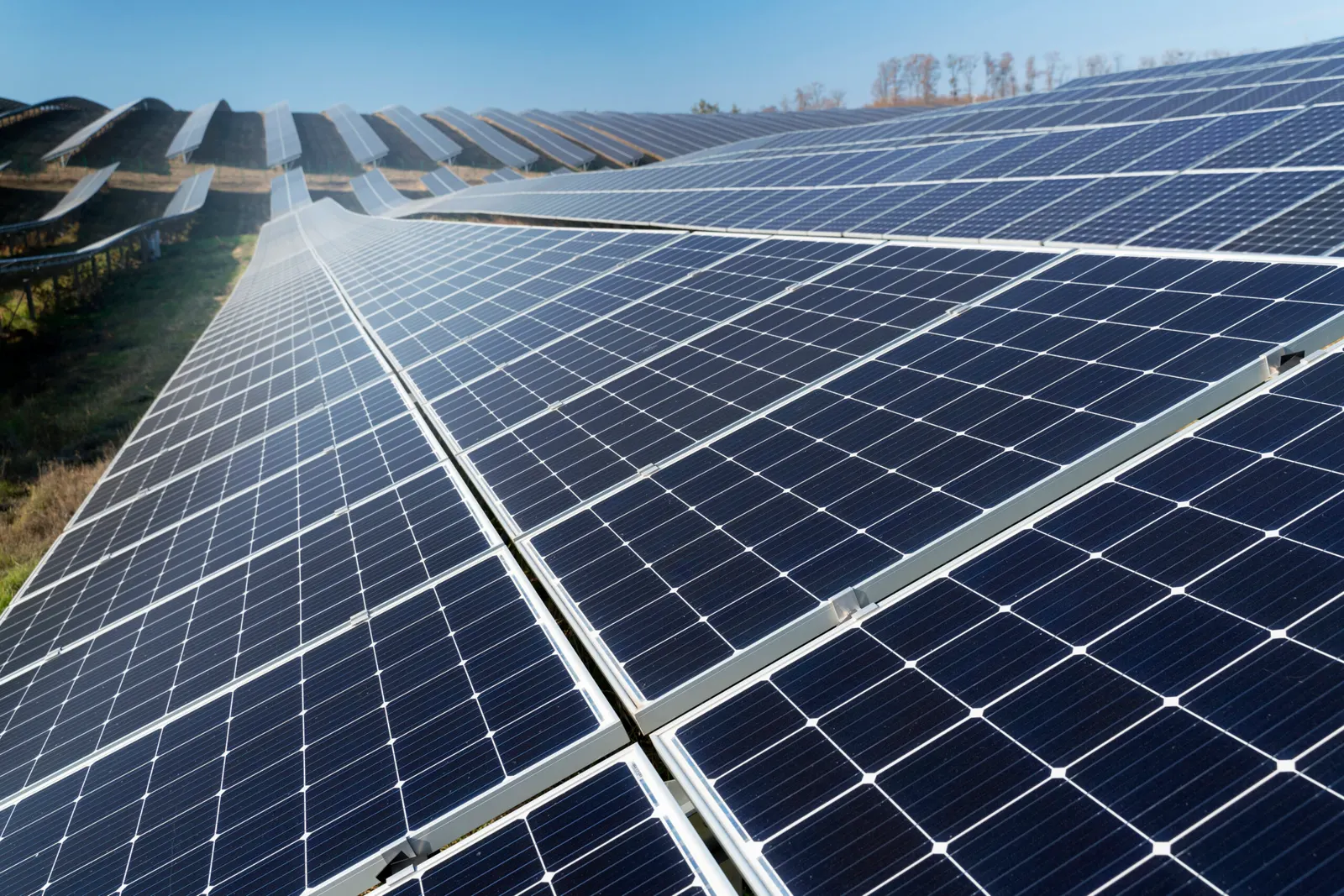 A row of solar panels in an open field under a clear sky