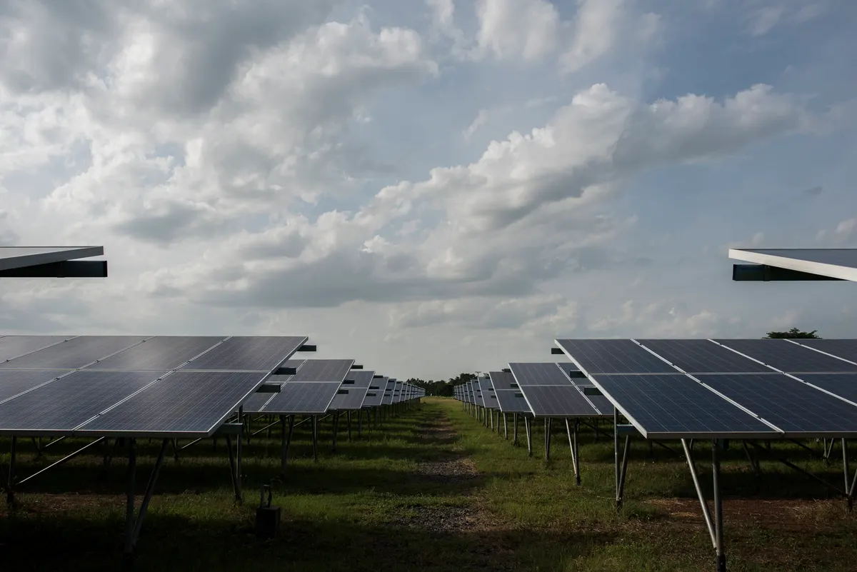 Rows of ground-mounted solar panels under tropical cloud