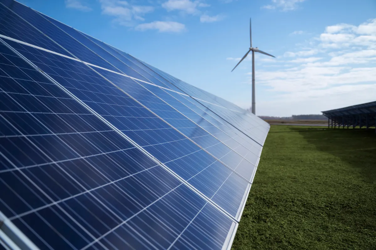 Solar panels and a wind turbine in an open field