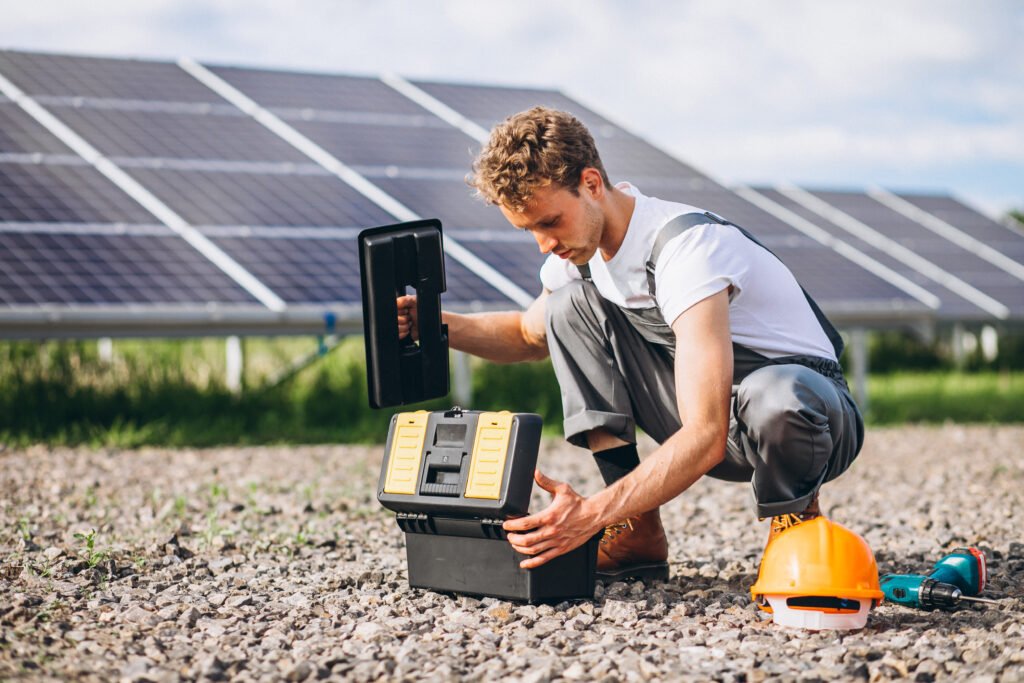 Technician working near solar panels in field – battery and inverter installation